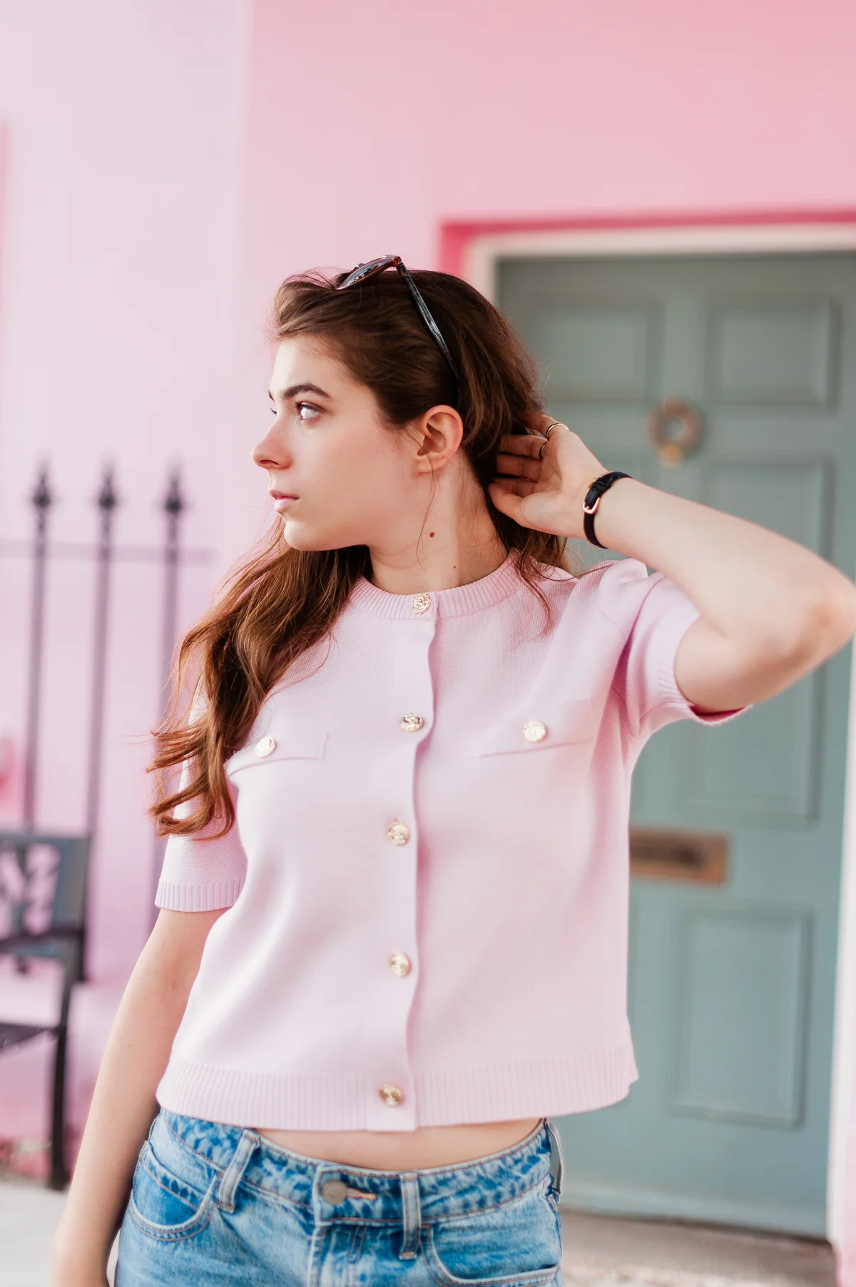Julia in a blush pink knit, looking to the side in front of a pink façade